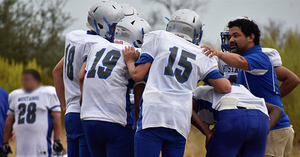The Mustangs football players huddle up for the next play.