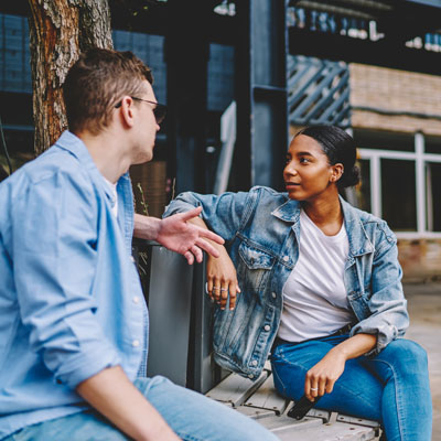 An image of a couple having a discussion on a park bench.