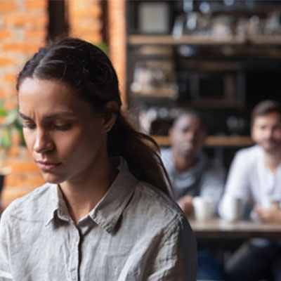 An image of a girl sitting in a coffee shop and looking at her laptop.