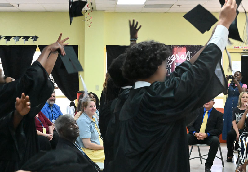 Youth toss their caps in the air to celebrate at the Mart graduation ceremony.